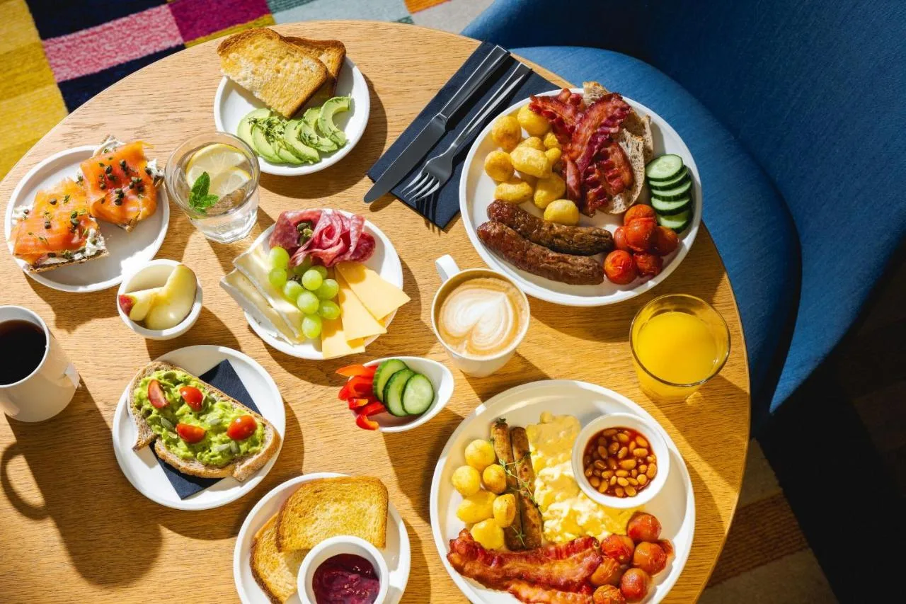 a wooden table with plates of food on it at citizenM London Bankside in London