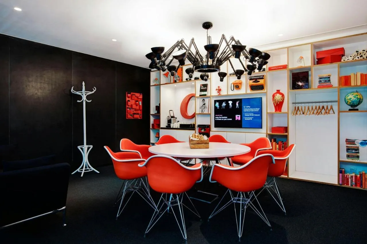 a dining room with a table and red chairs at citizenM London Bankside in London