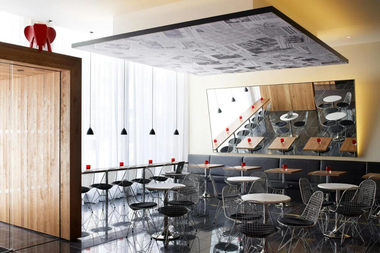 a room with tables and chairs and a staircase at citizenM London Bankside in London